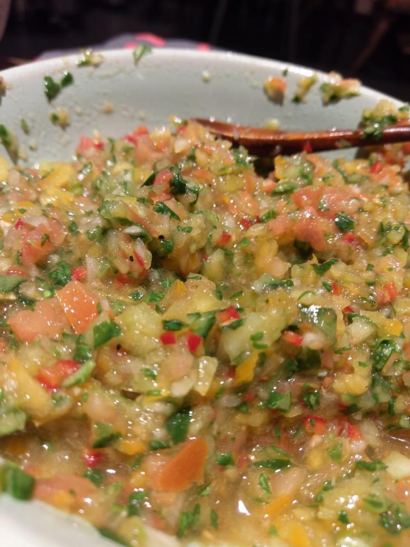 A yellow, green salsa with specks of red chillies, pretty moist looking.