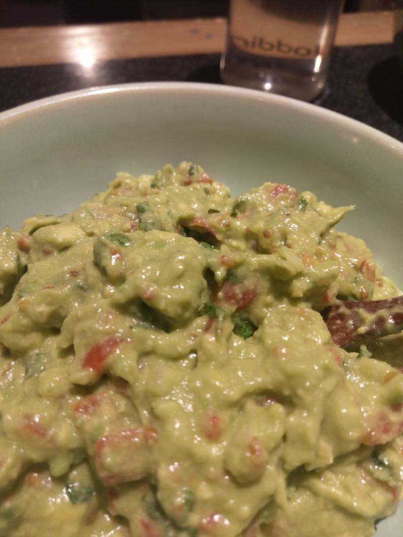 guacamole, a green avocado dish with red chillies, cherry tomatoes, peppers and fresh coriander