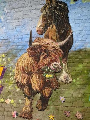 A mural of a Highland cow eating grass.