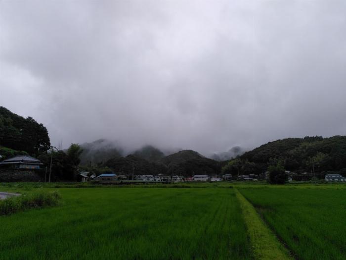 heavy looking clouds rolling over the nearby hills, some green rice fields also populate the picture