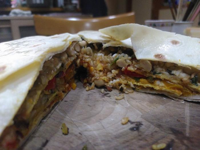 The giant burrito cake with some slices cut out revealing the layered contents inside.