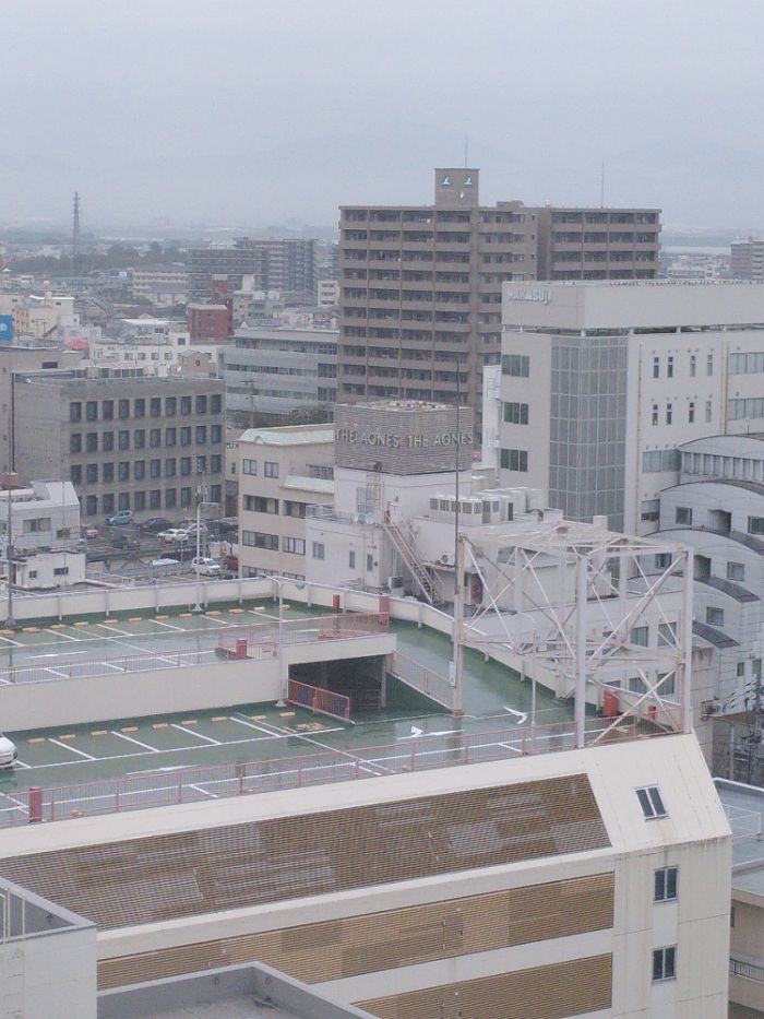 a largely white rooftop view from an 11th floor hotel room, one of the taller buildings has a sign on each of its visible walls saying "The Agnes"