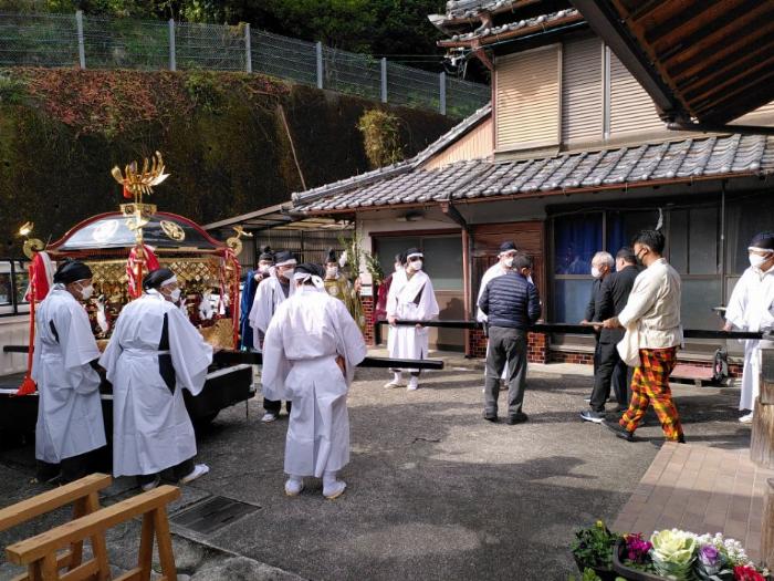 various folk, some in Shinto attire are unloading a very shiny mobile shrine from the back of a white kei truck.