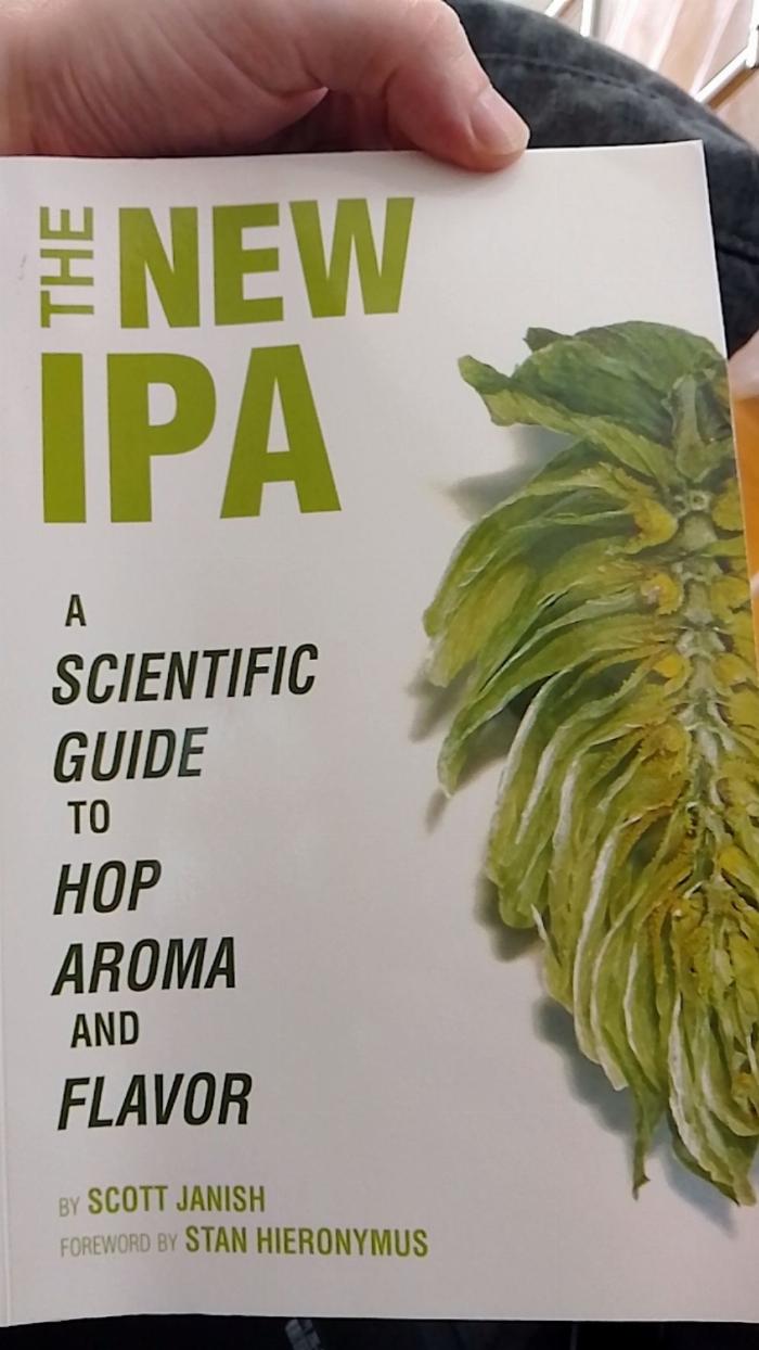 The cover of a book called The New IPA, it is plain white with green text and a dissected hop cone on the cover