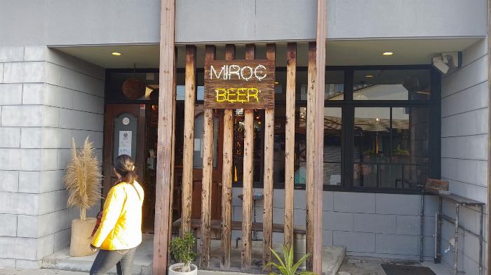 outside of the pub are some wooden pillars and a neon sign reading Miroc Beer