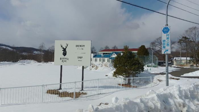 背景には古い小学校、手前には学校の体育館にある醸造所「ブラッスリー・ノット」の看板がある雪景色。